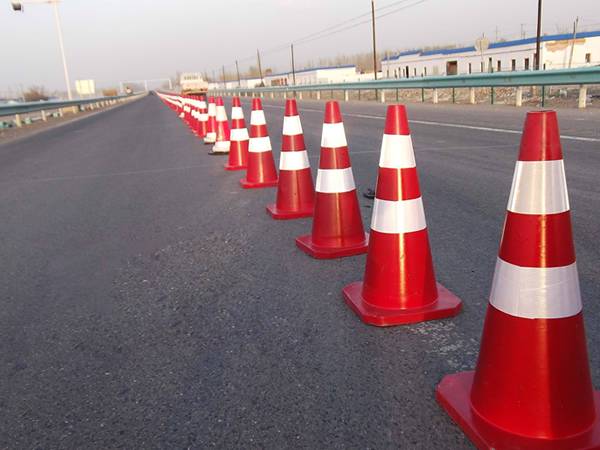 A row of PVC reflective traffic cone is placed along the road.